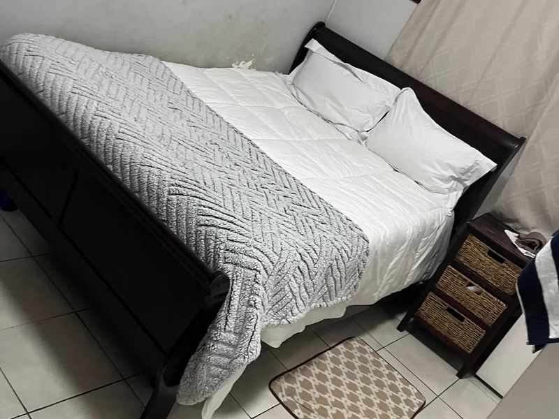 A bedroom featuring tiled flooring and neutral wall finishes, currently furnished with a bed and bedside storage.