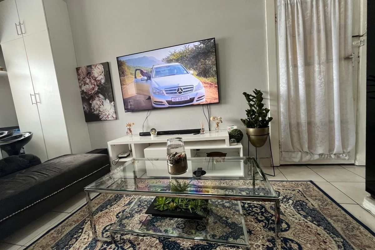 A living room area featuring tiled flooring and a built-in storage cupboard, providing a functional space for relaxation.