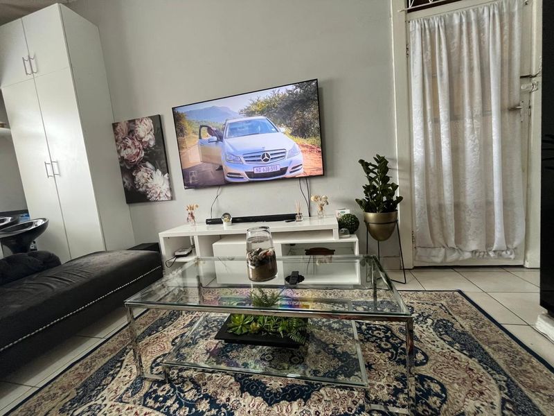 A living room area featuring tiled flooring and a built-in storage cupboard, providing a functional space for relaxation.