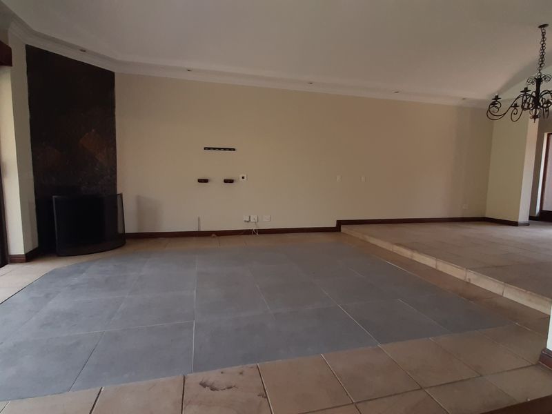 Spacious living area featuring a built-in fireplace, tiled flooring with a raised platform section, and large sliding glass doors leading to the exterior.