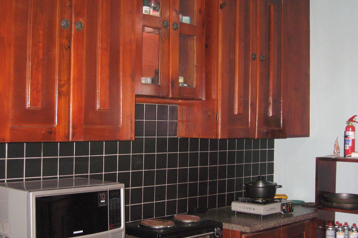 A kitchen area featuring dark wooden cabinetry, a black tiled backsplash, and a laminate countertop with a built-in oven.