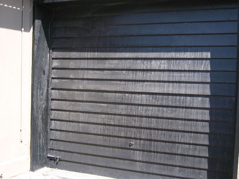 A close-up view of a black sectional garage door showing visible surface staining and weathering.