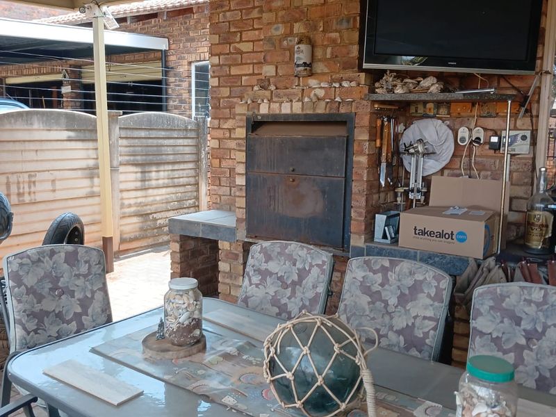 Covered outdoor patio area featuring a built-in brick braai and paved flooring, suitable for outdoor entertaining.