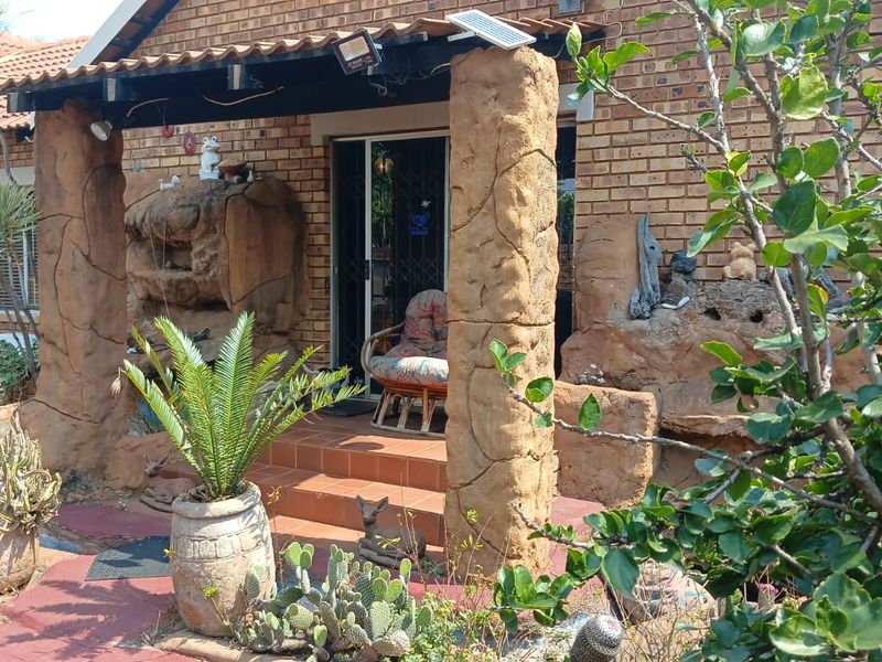 A covered patio area featuring unique rock-style pillars, tiled flooring, and a sliding glass door entrance to the home.