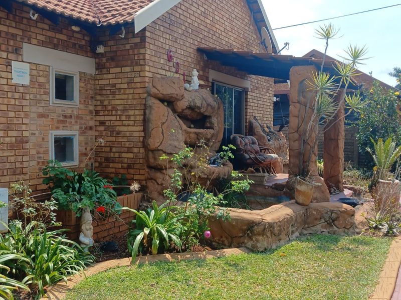 Front exterior view of a face brick house featuring a decorative rock facade element, paved walkway, and established garden area.