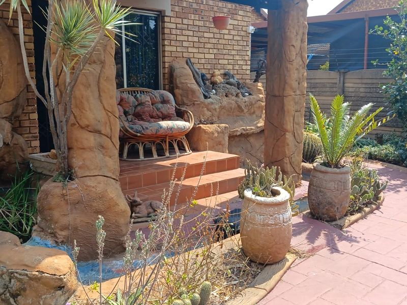 A covered patio area featuring unique decorative rock-style pillars and a built-in rock water feature, providing a rustic outdoor living space.