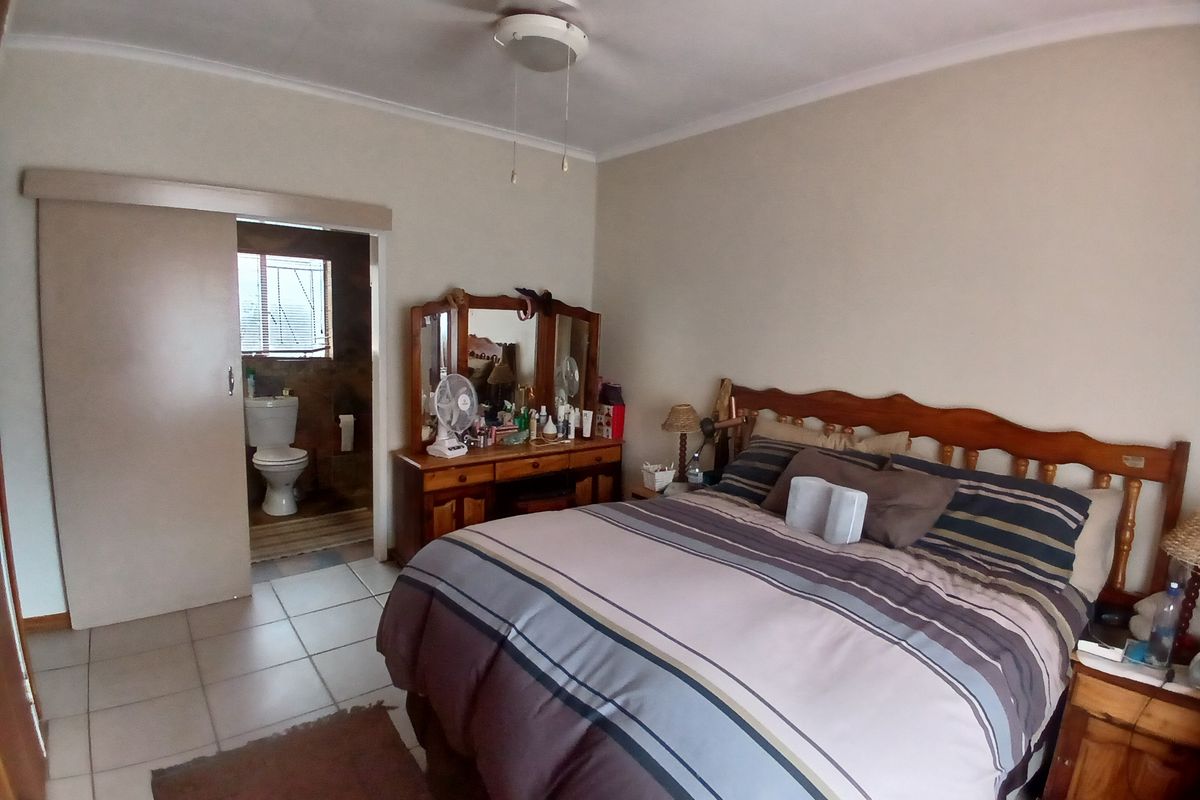 A bedroom featuring tiled flooring, a ceiling fan, and an adjoining en-suite bathroom accessed via a sliding door.