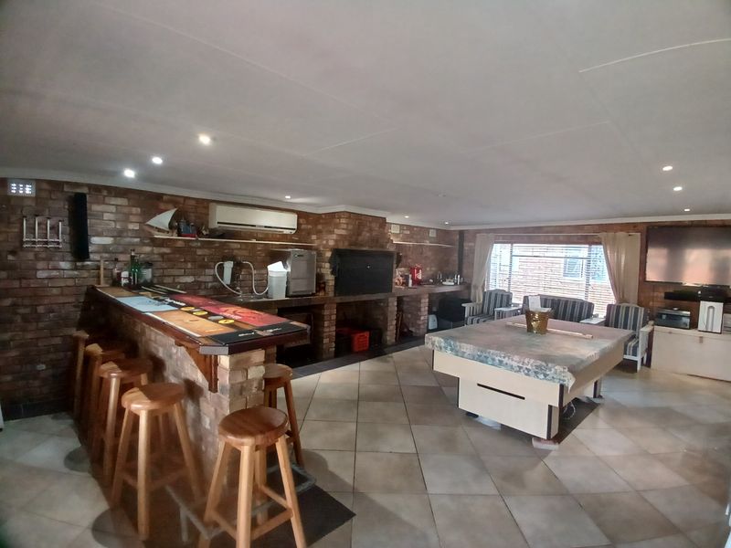 Spacious entertainment room featuring a built-in brick bar, integrated fireplace, tiled flooring, and recessed lighting, offering a functional space for social gatherings.
