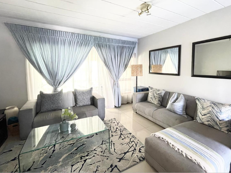 A bright and well-maintained living room featuring tiled flooring and neutral wall finishes, offering a comfortable and inviting space.