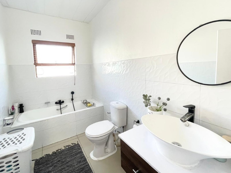 A modern bathroom featuring a built-in bathtub, a vessel sink on a vanity cabinet, and contemporary black fixtures.