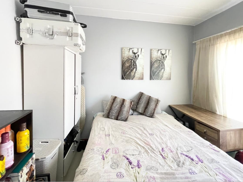 A compact bedroom featuring a built-in desk and window with curtain rail, offering a functional space for rest or study.