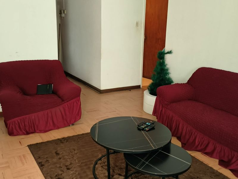 A living room area featuring parquet flooring and neutral wall finishes, providing a functional space for relaxation.