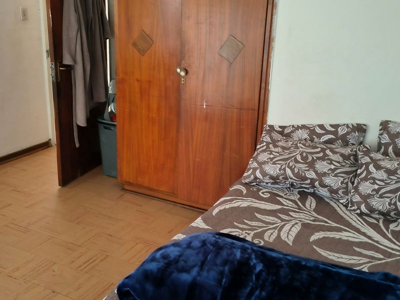A bedroom featuring parquet flooring and a built-in wooden wardrobe, requiring cosmetic updates to improve the overall aesthetic.