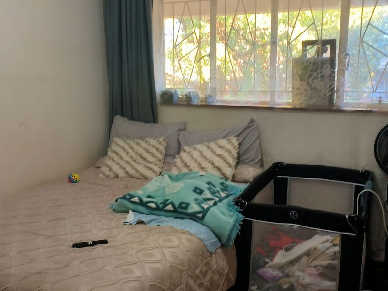 A bedroom featuring a window with security bars, requiring cosmetic updates to the wall finishes.