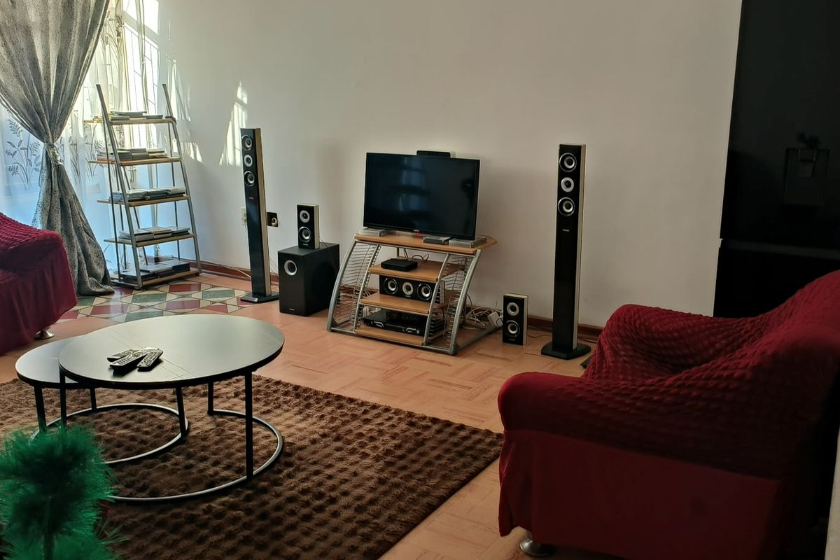 A living room featuring parquet flooring and a large window, providing a functional space for relaxation.