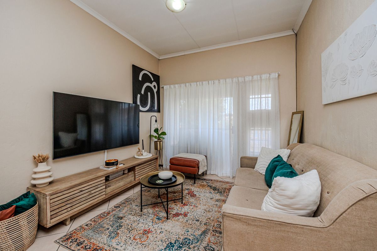 A cozy living room featuring tiled flooring and a sliding glass door that provides access to the exterior.