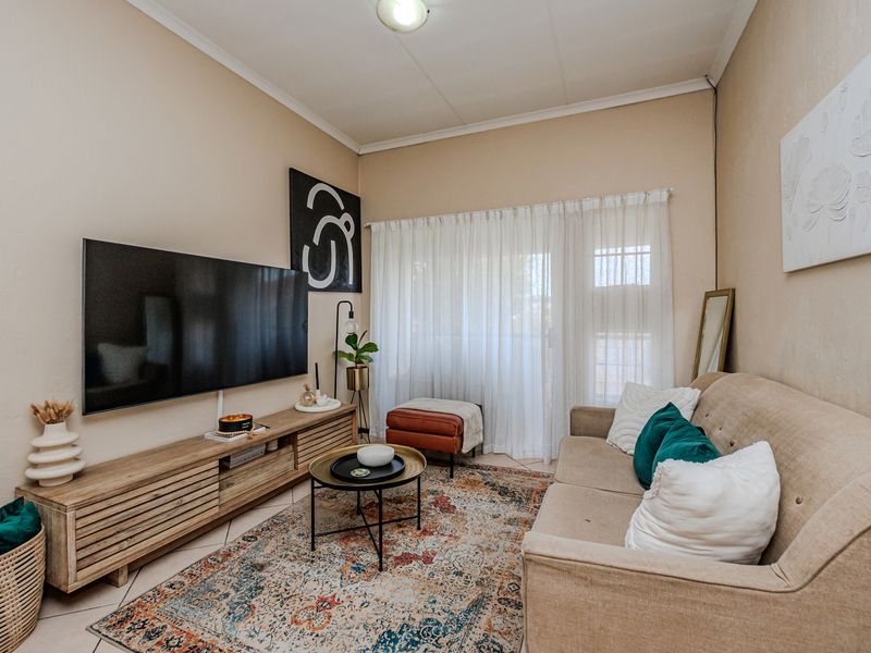 A cozy living room featuring tiled flooring and a sliding glass door that provides access to the exterior.