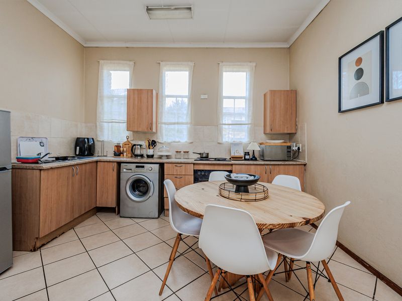 Functional kitchen featuring laminate cabinetry, tiled flooring, built-in oven, and hob, with an integrated space for a washing machine.