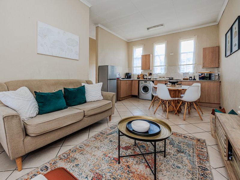 Open-plan living and kitchen area featuring tiled flooring, functional cabinetry, and a practical layout suitable for modern apartment living.