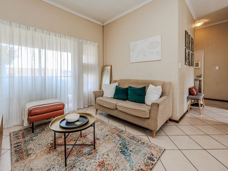 A bright living room featuring tiled flooring and a large sliding glass door that provides access to the outdoor area.