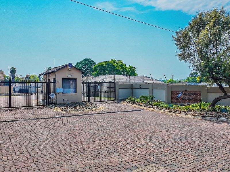 The entrance to the estate features a secure gated access point, a guard house, and perimeter walling with electric fencing.