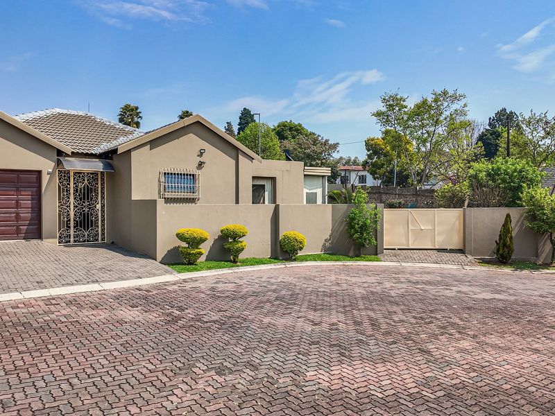 Front elevation of a single-story house featuring a paved driveway, single garage, and secure perimeter walling with gated access.