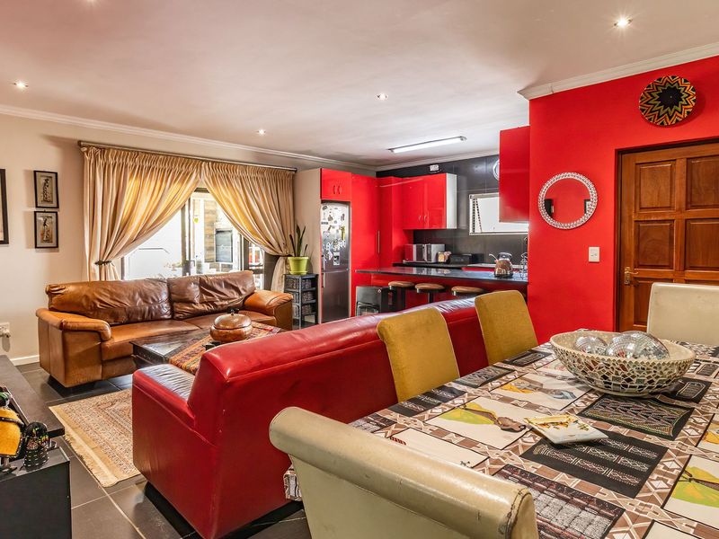 An open-plan living, dining, and kitchen area featuring tiled floors, recessed lighting, and a modern kitchen with built-in cabinetry and a breakfast bar.