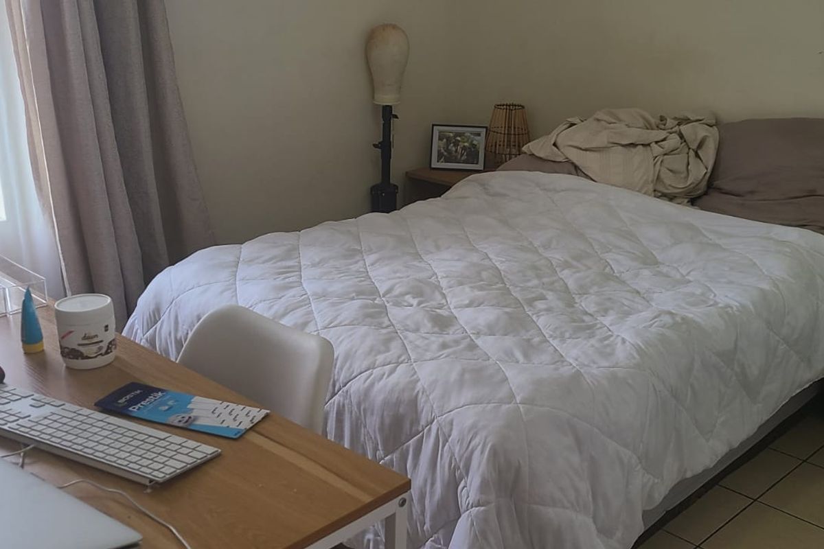 A functional bedroom featuring tiled flooring and natural light from the window, providing a comfortable space for rest.