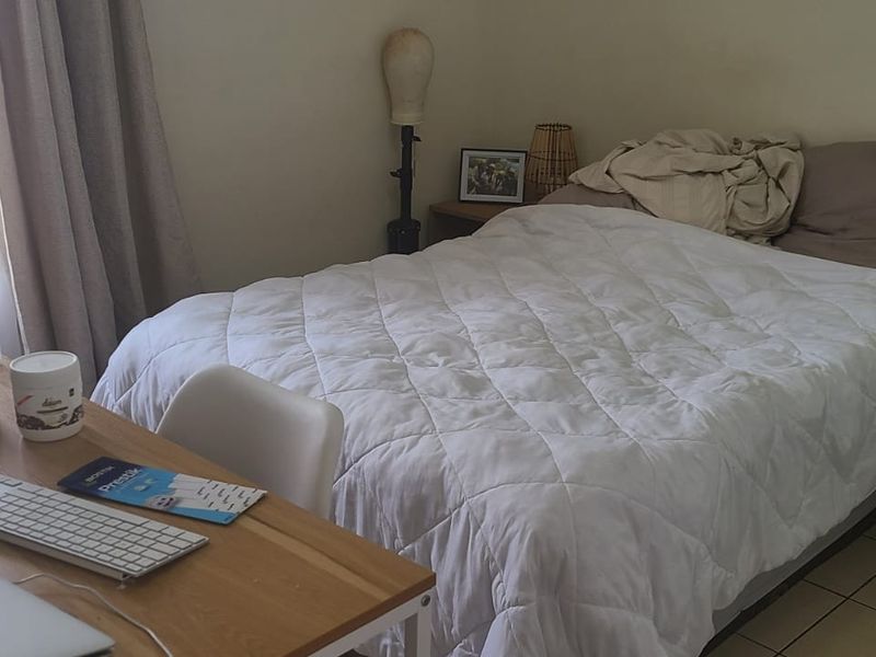 A functional bedroom featuring tiled flooring and natural light from the window, providing a comfortable space for rest.