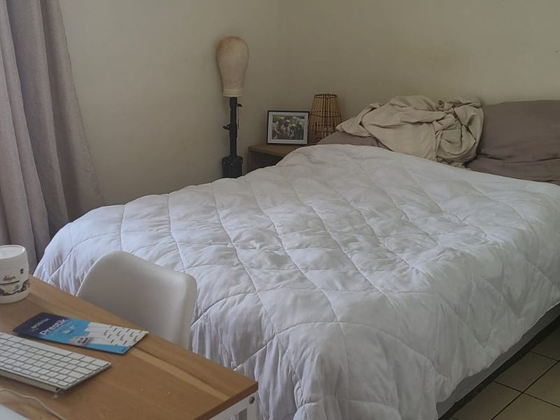 A standard bedroom featuring tiled flooring and neutral wall finishes, providing a functional space for rest.