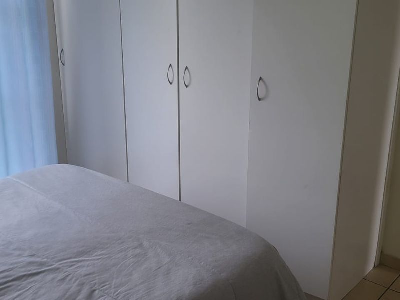 Bedroom featuring built-in cupboards, tiled flooring, and a sliding glass door providing natural light and outdoor access.