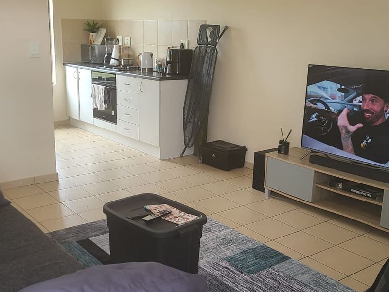 Open-plan living area featuring tiled flooring and a functional kitchen with built-in cabinetry and oven, creating a combined living and cooking space.