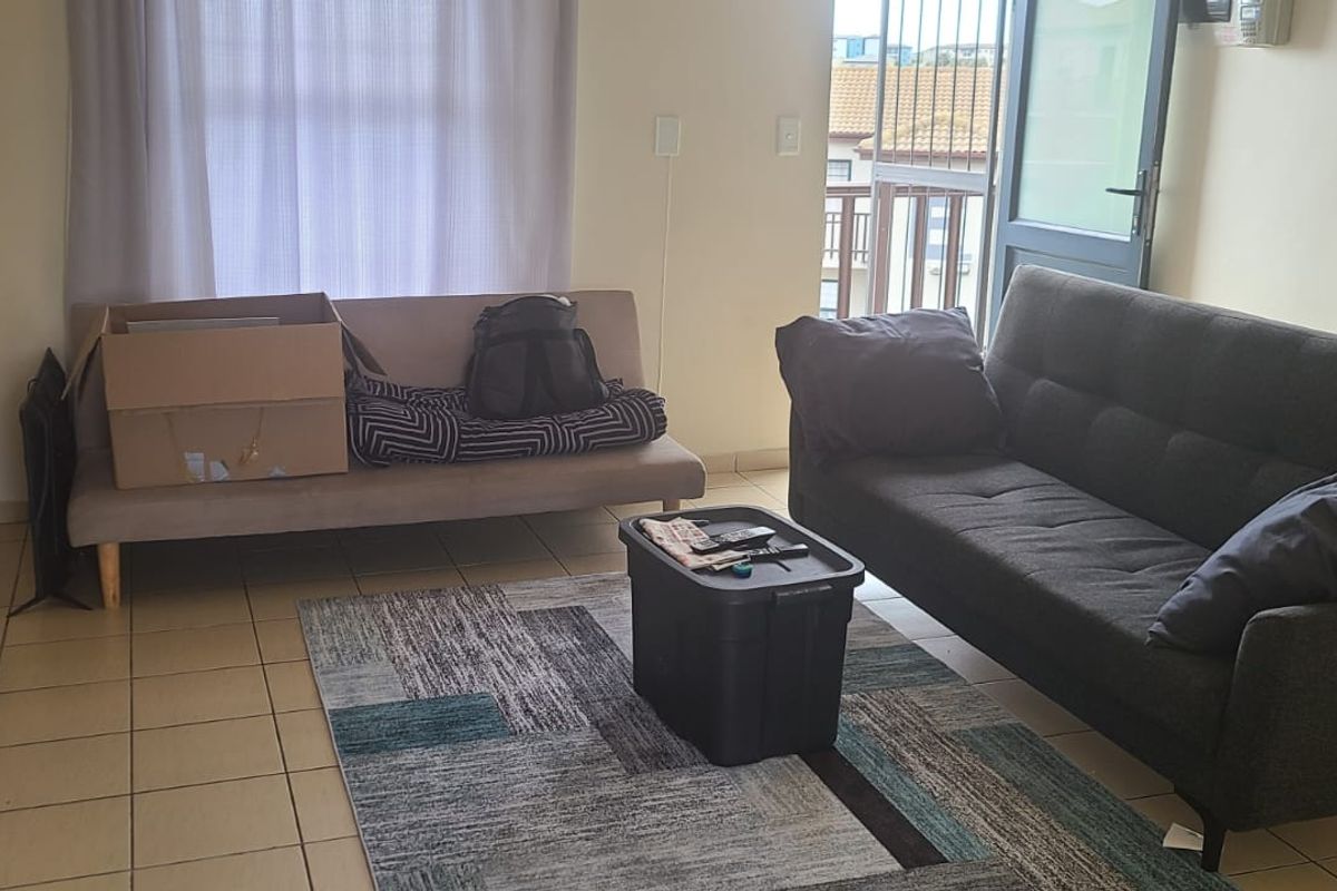 A living room area featuring tiled flooring and a sliding door providing access to an outdoor balcony space.