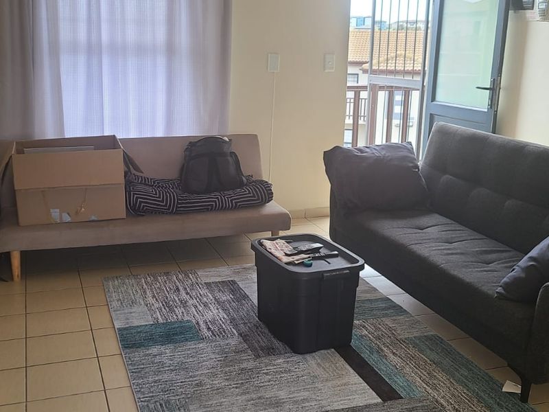 A living room area featuring tiled flooring and a sliding door providing access to an outdoor balcony space.