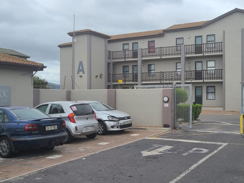 Exterior view of Southwark Mews apartment complex featuring a paved parking area, security gate, and multi-story residential building with balconies.