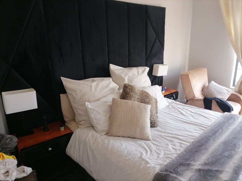 A comfortable bedroom featuring a large, dark upholstered headboard as a central design element.