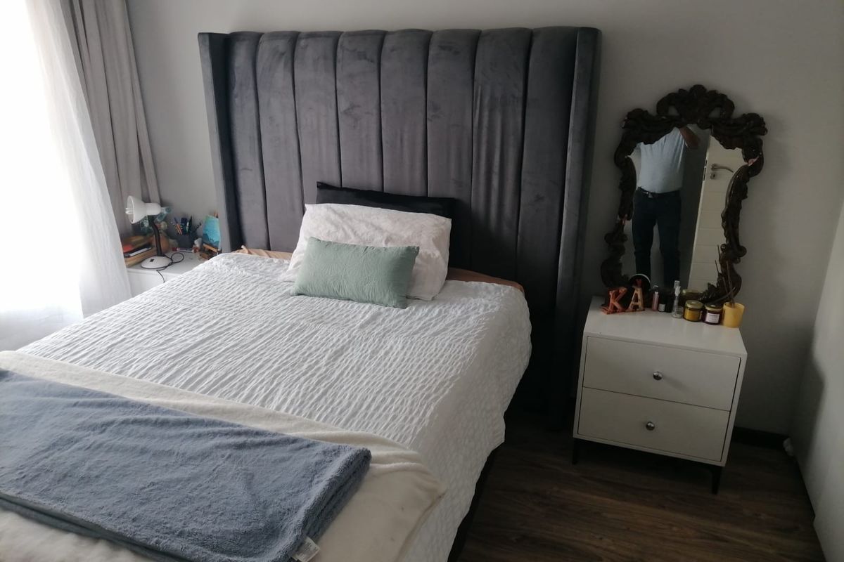 A well-maintained bedroom featuring laminate flooring and neutral wall finishes, providing a comfortable and functional sleeping space.