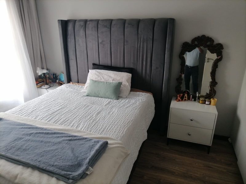 A well-maintained bedroom featuring laminate flooring and neutral wall finishes, providing a comfortable and functional sleeping space.