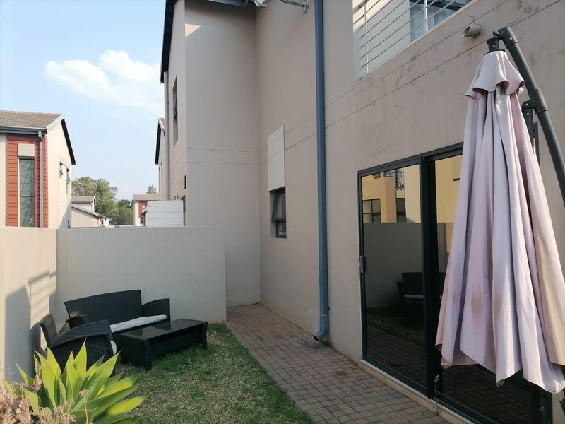 A view of the rear exterior of the house featuring a paved walkway, a small lawn area, and a sliding glass door entrance.