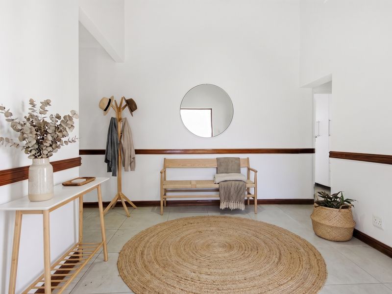A bright and welcoming entrance hall featuring neutral tiled flooring and classic wooden dado rail detailing.
