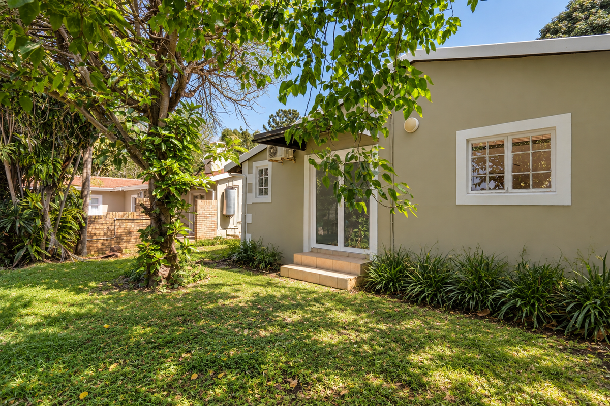Rear view of the property featuring a well-maintained garden, paved entrance steps, and access via white-framed french doors.