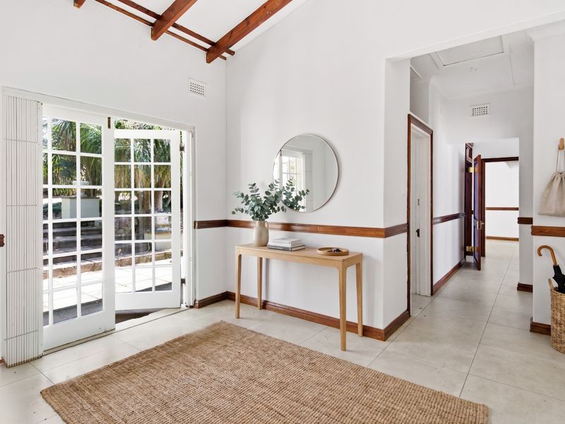 Bright and welcoming entrance hall featuring exposed timber ceiling beams, tiled flooring, and classic french doors leading to the outdoor area.