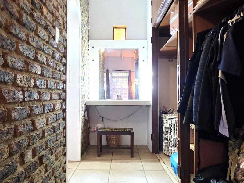 A bedroom featuring an exposed brick wall, tiled flooring, and extensive built-in cupboard storage with an integrated vanity area.
