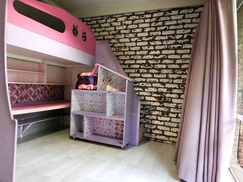 A bedroom featuring a distinctive exposed brick wall, laminate flooring, and a large sliding glass door providing natural light and garden access.