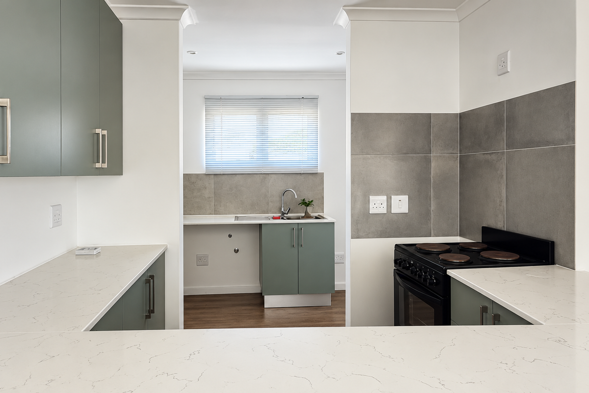 Modern kitchen featuring sleek green cabinetry, quartz countertops, a tiled backsplash, and a built-in electric stove, offering a clean and functional workspace.