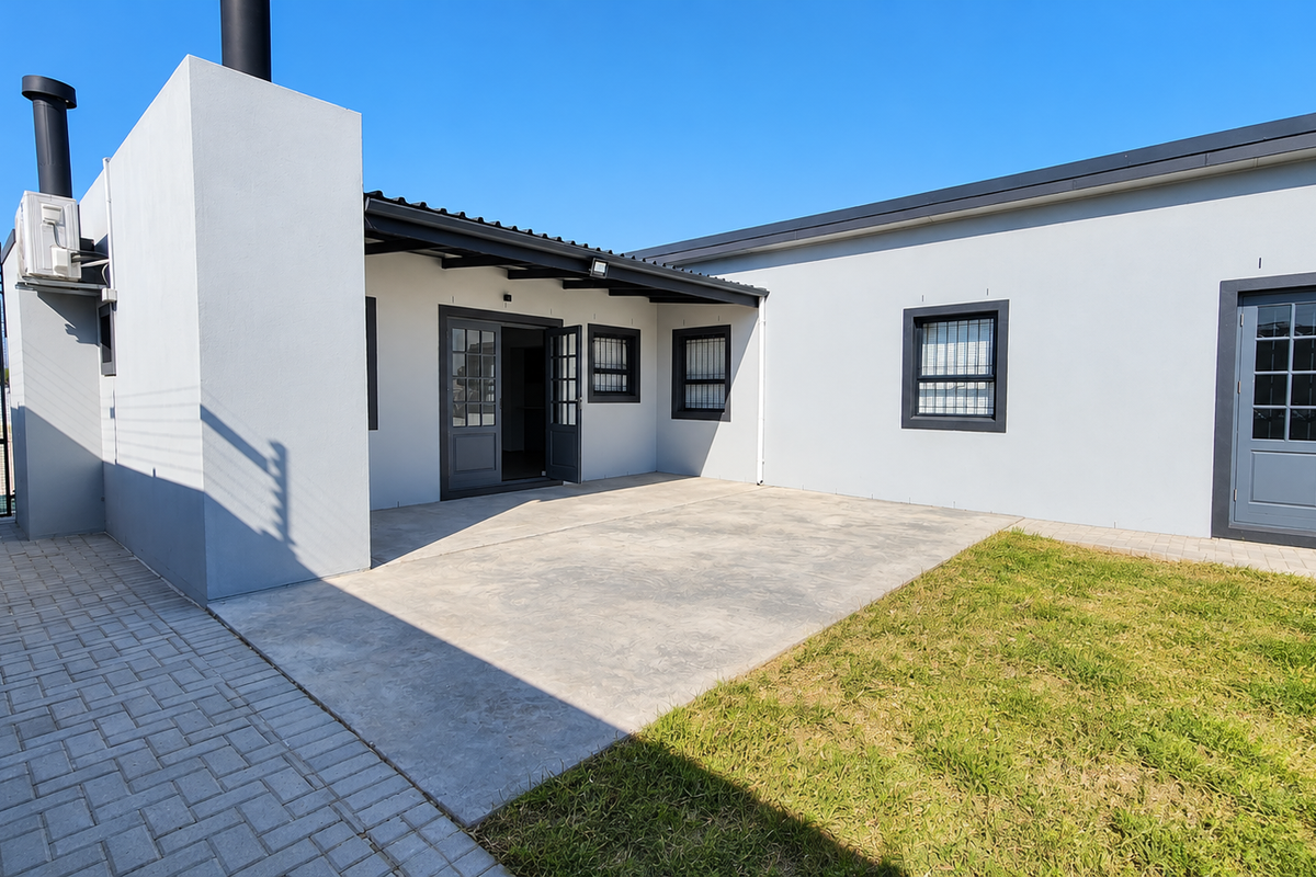 A well-maintained rear exterior featuring a concrete patio, paved areas, secure french doors, and external infrastructure including an air conditioning unit and chimney flue.