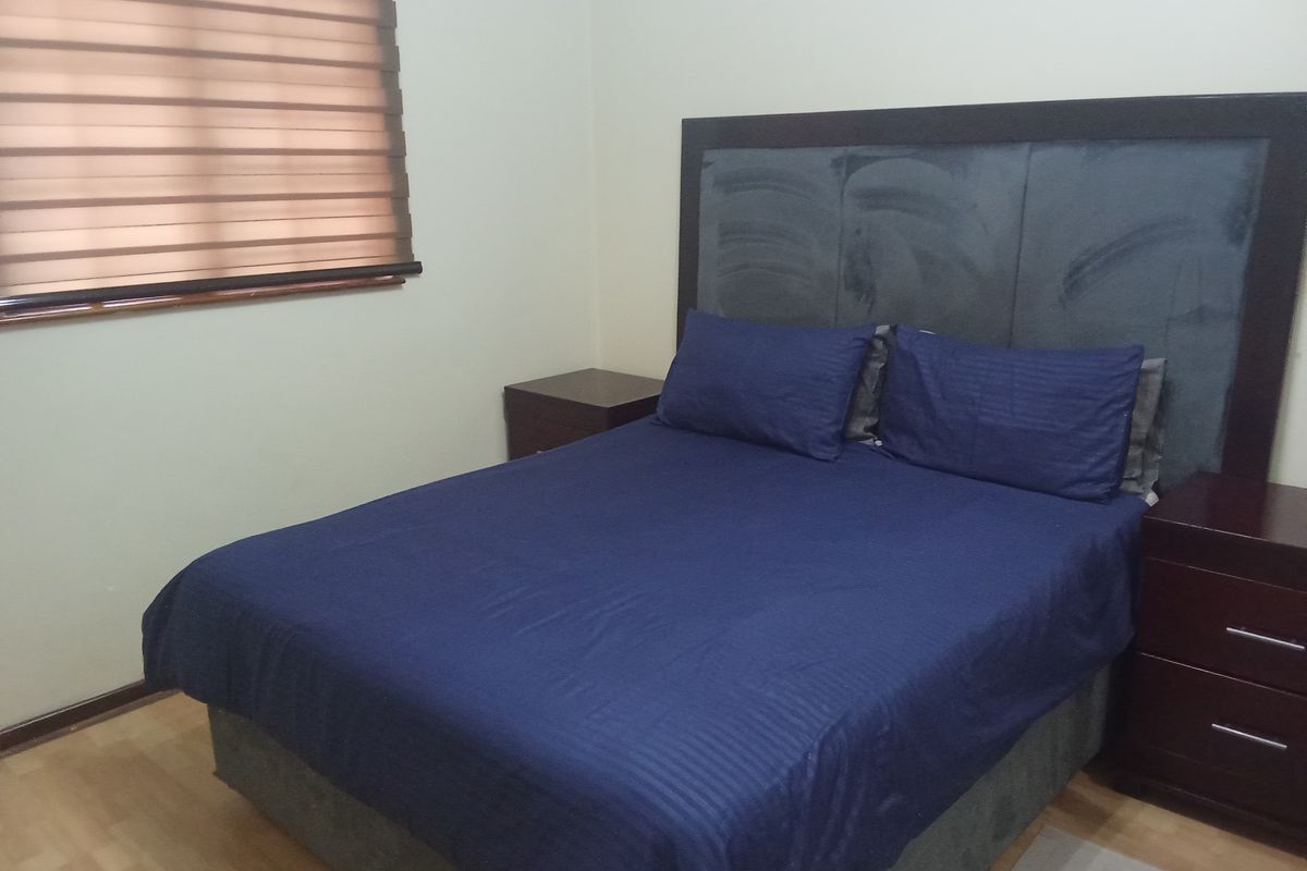 A bedroom featuring laminate flooring and zebra blinds, providing a functional space with neutral wall finishes.