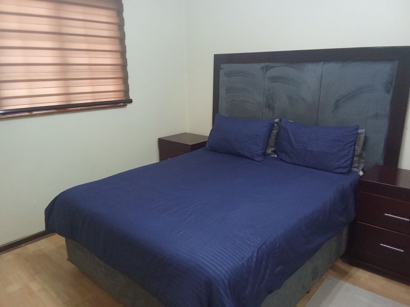 A bedroom featuring laminate flooring and zebra blinds, providing a functional space with neutral wall finishes.