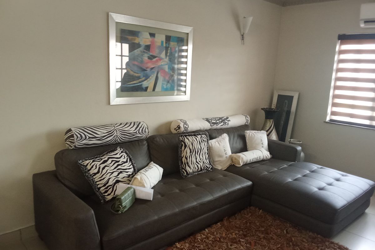 A comfortable living room featuring crown molding, an integrated air conditioning unit, and modern roller blinds on the window.