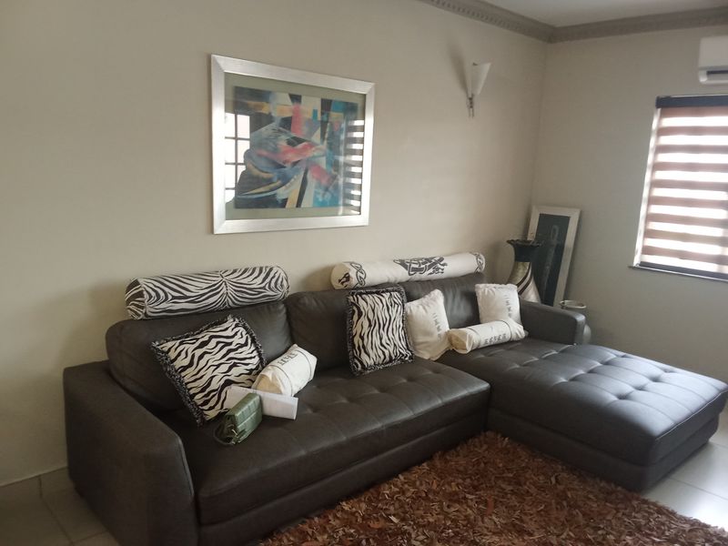 A comfortable living room featuring crown molding, an integrated air conditioning unit, and modern roller blinds on the window.